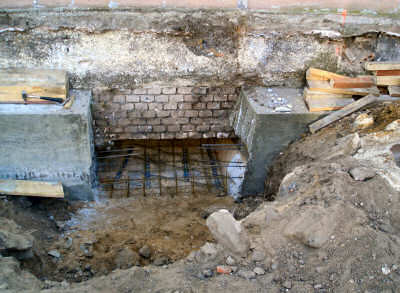 Da die Fundamente der verbleibenden Gebäudeteile nicht tragfähig genug sind, werden diese zur Sicherung mit Beton unterfangen.